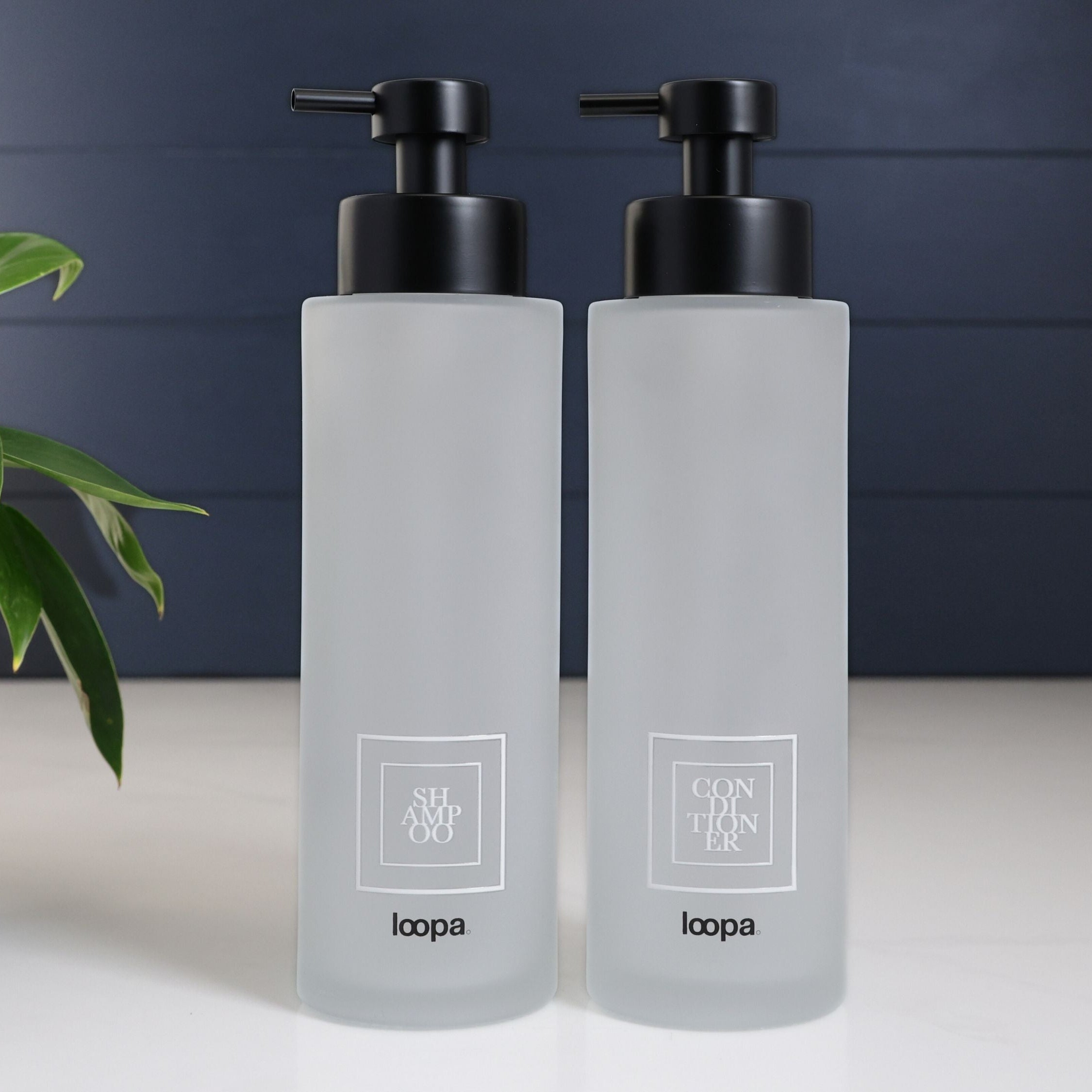Square frosted glass dispenser bottle with a white label, styled as a refillable piece for clean, modern bathroom or kitchen spaces