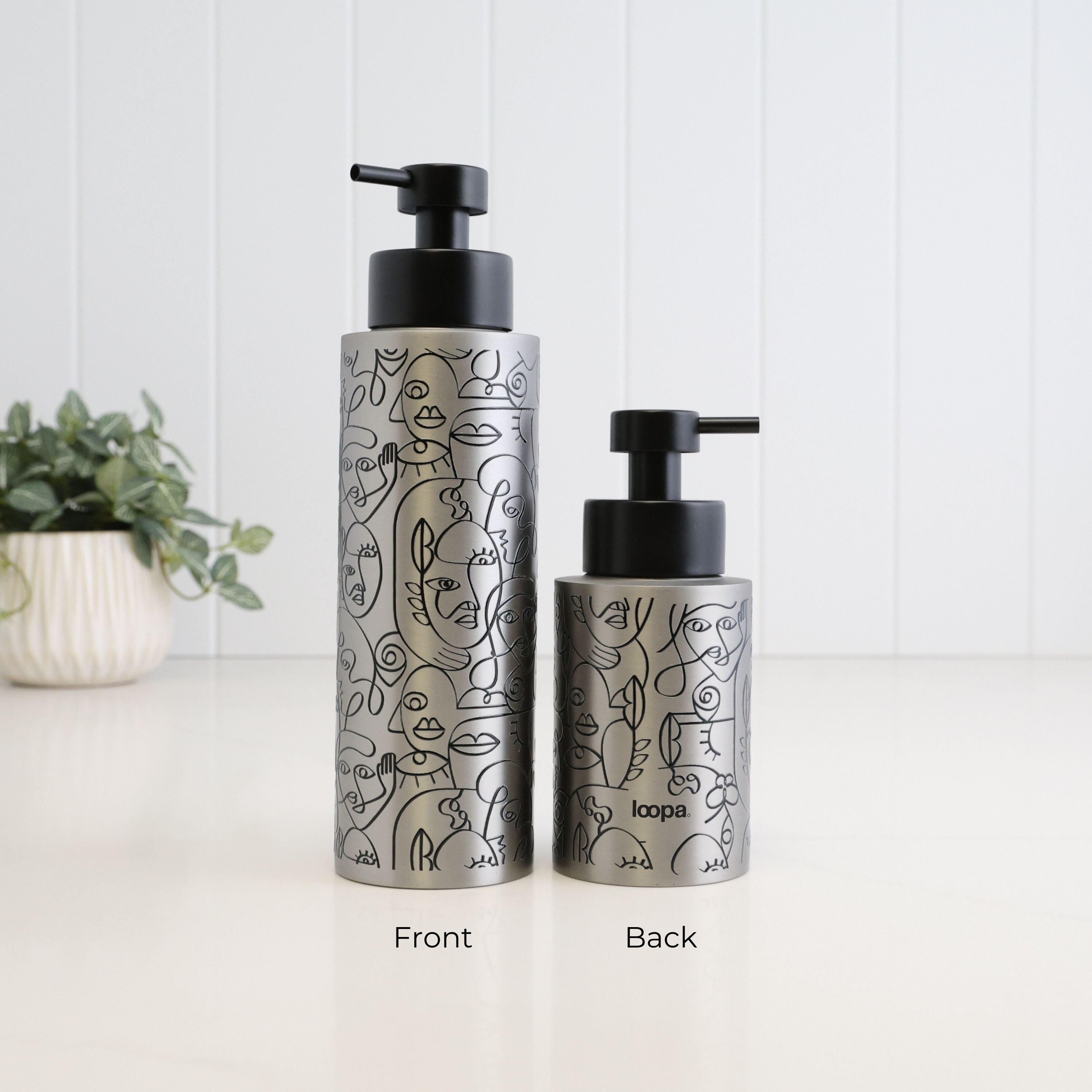 Front and back views of brushed 304 stainless steel soap dispensers in 500ml and 250ml sizes, finished with black abstract face line art, satin black liquid pumps and Loopa branding.