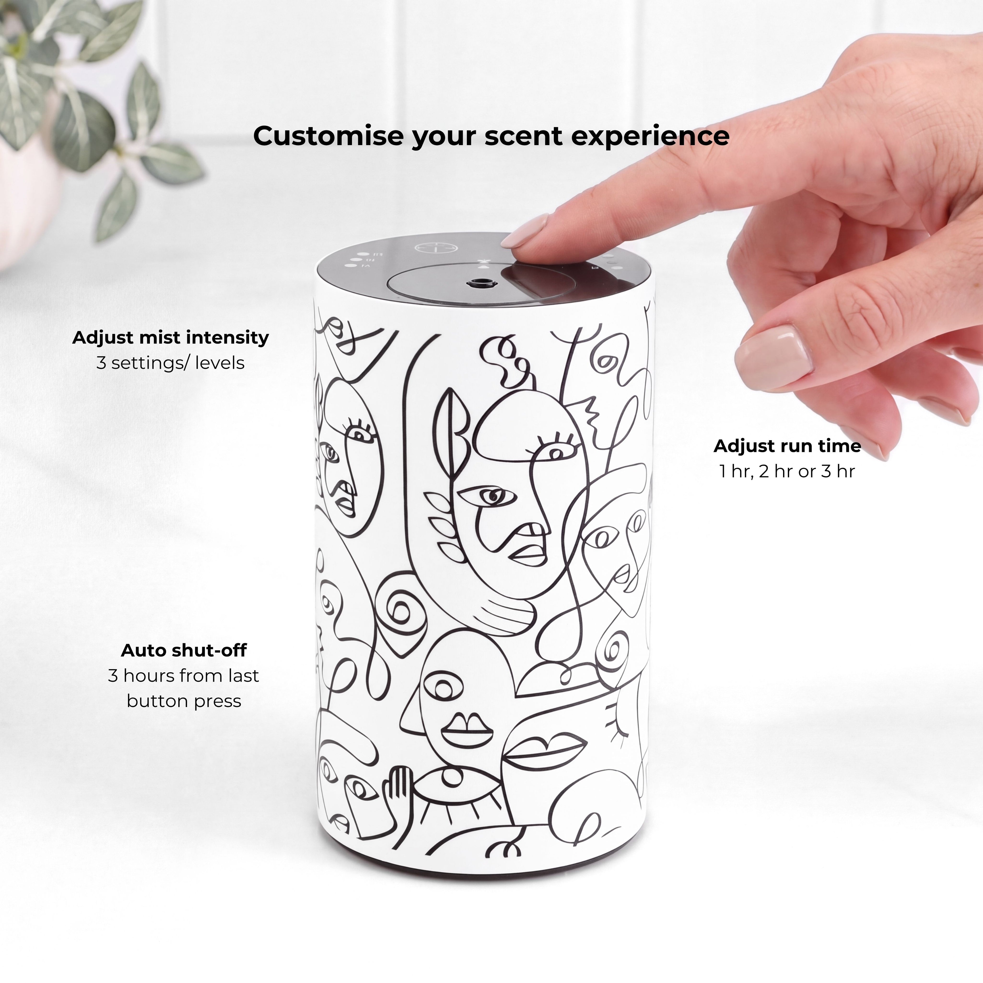 Loopa white waterless essential oil diffuser with black abstract face illustrations, showing a hand operating the touch controls on its top panel. Features three adjustable fragrance mist intensity levels, selectable 1, 2 or 3 hour timer settings and automatic shut-off three hours after the last button press. This cordless rechargeable aromatherapy diffuser allows personalised home fragrance without water or heat.